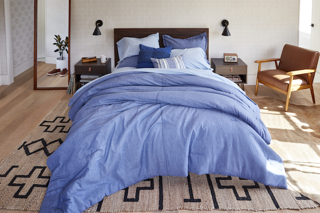 A bed is draped in different shades of blue bedding.