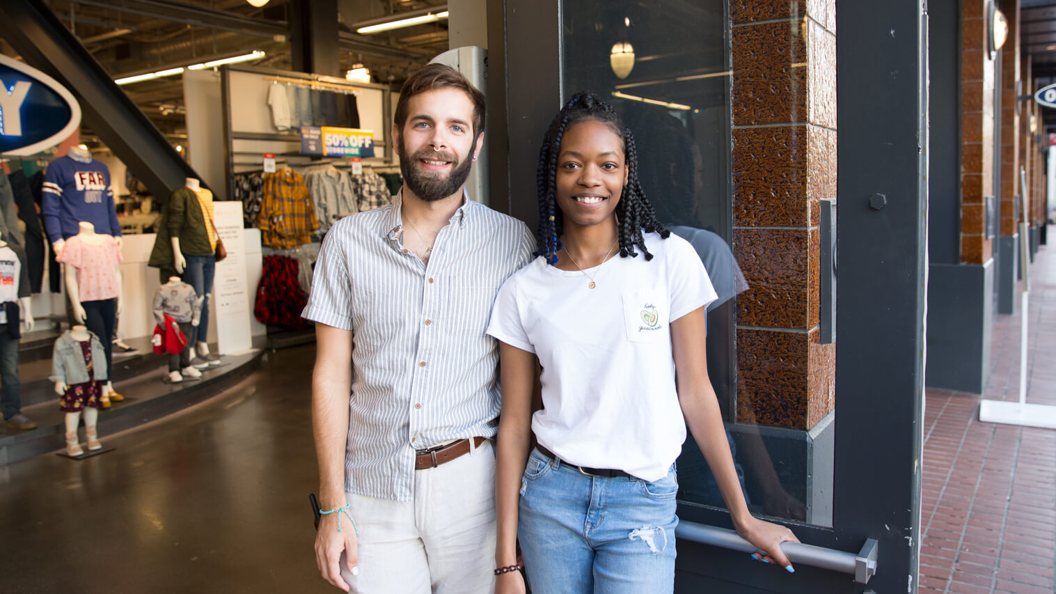 Two employees standing my store entrance welcoming guests